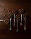 Six cuillères en argent remplies de grains de café torréfiés artisanalement sur bois foncé